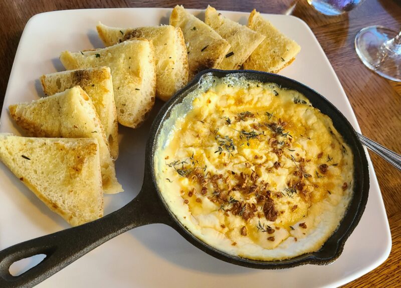 Honey- Crusted Baked Ricotta with Gewütztraminer herb honey, thyme, crispy garlic and lemon peel on the menu at  Messina Hof's Vintage House Restaurant.