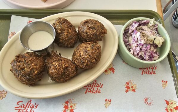 Bright green falafel plate with tahini and a side of fennel tzatziki slaw