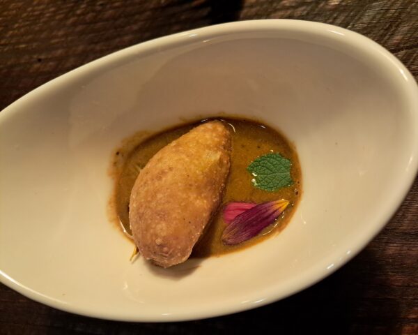 Louisiana crawfish bisque with a crawfish tail mandazi (a type of beignet), smoked grapes and miso scented shallots
